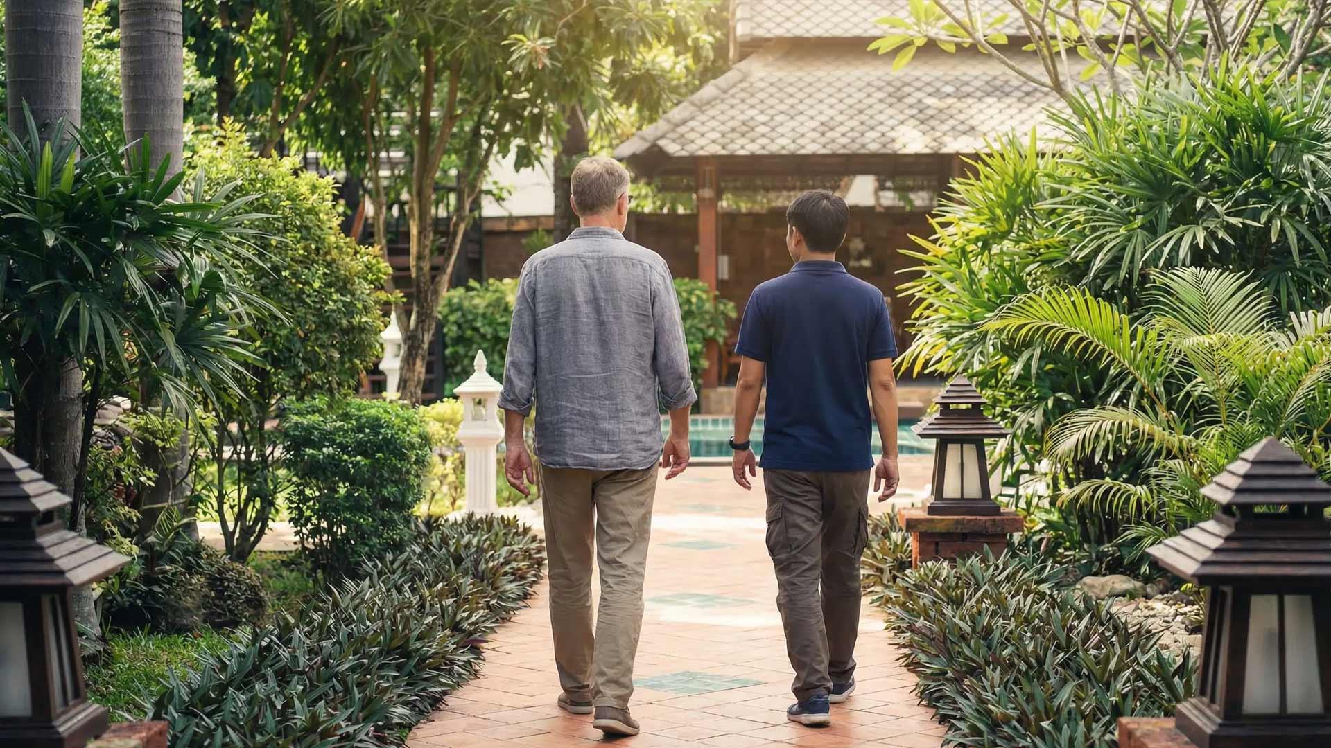 Two individuals walking along a garden path at Jintara Rehab in Chiang Mai