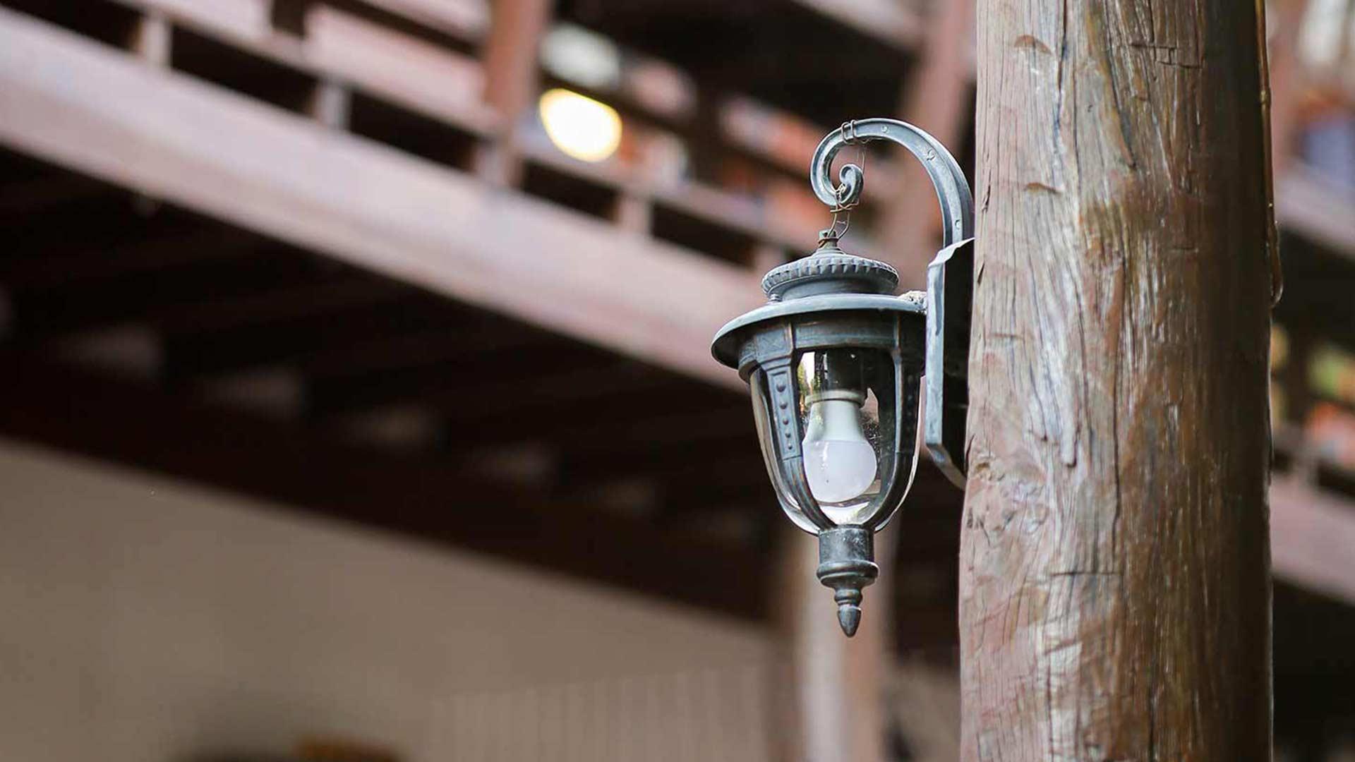 Vintage iron lantern on a wooden pillar beneath Lanna timber eaves at Jintara Rehab