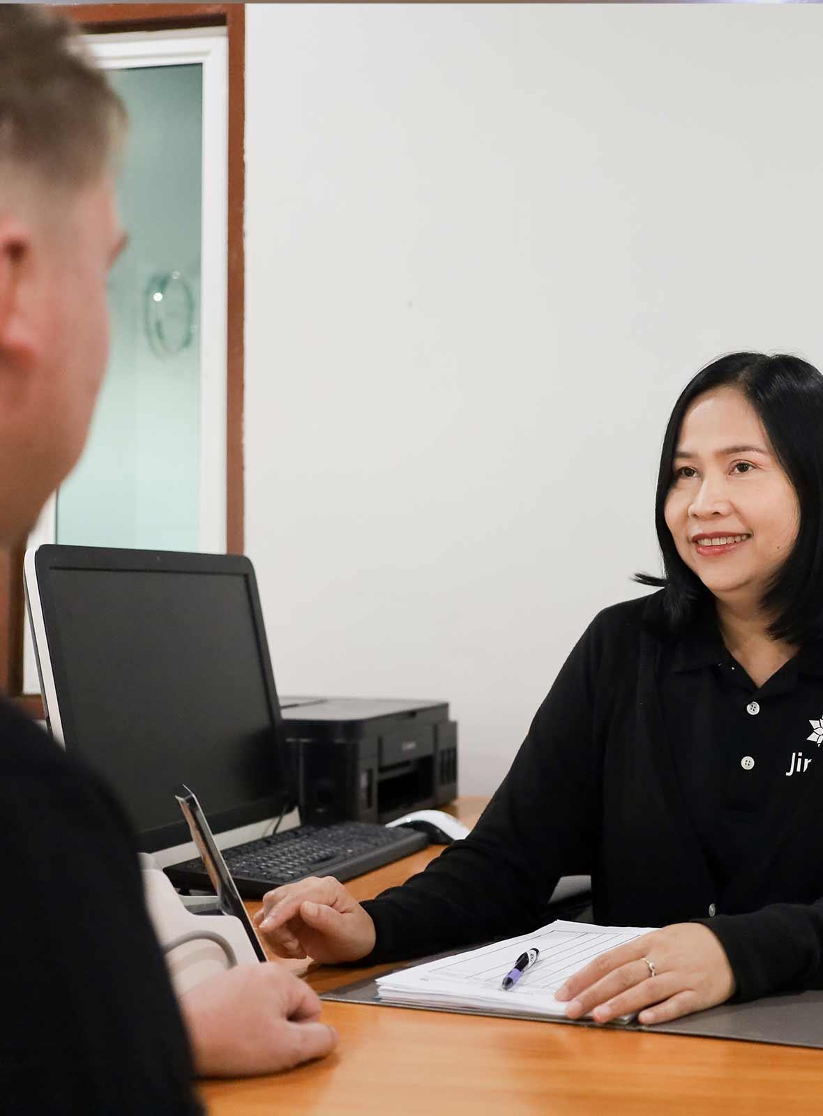 Nurse reviewing admission forms with a client at the nursing desk at Jintara Rehab