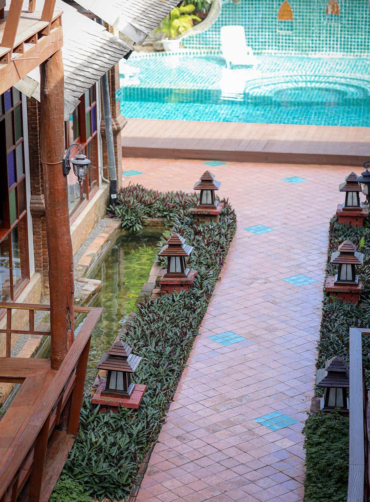 Aerial view of tiled pathway with lanterns and pool edge at Jintara Rehab Thailand